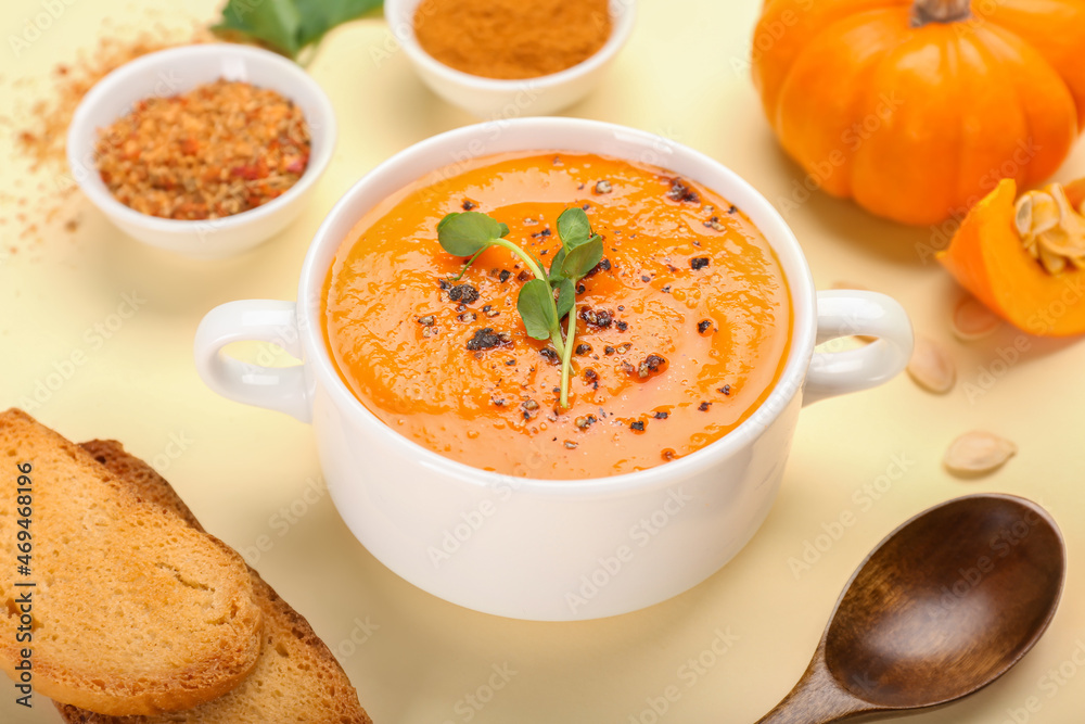 Pot with tasty pumpkin cream soup, spices and toasts on color background, closeup Pot with tasty pumpkin cream soup, spices and toasts on color background, closeup