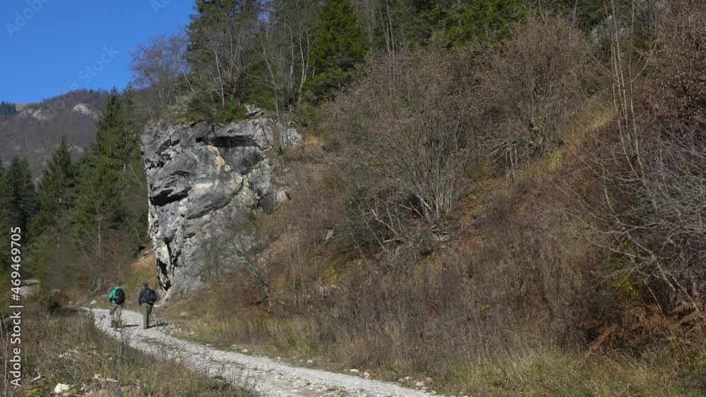 Hikers goes on forest path next to a large rock, Vlasic mountain Bosnia and Herzegovina - (4K) Hikers goes on forest path next to a large rock, Vlasic mountain Bosnia and Herzegovina - (4K)