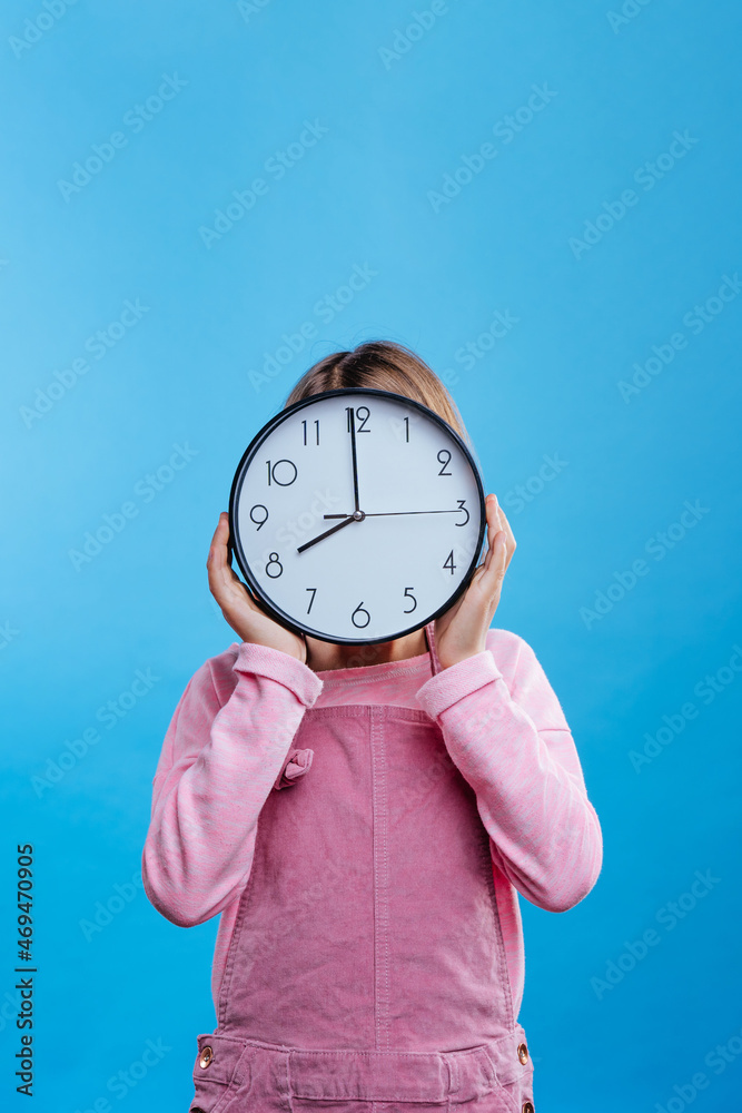 Little girl holding clock on blue background Little girl holding clock on blue background