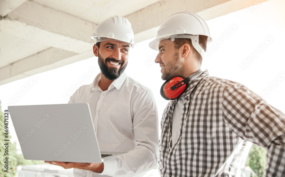 Smiling engineers discussing project while using laptop Smiling engineers discussing project while using laptop