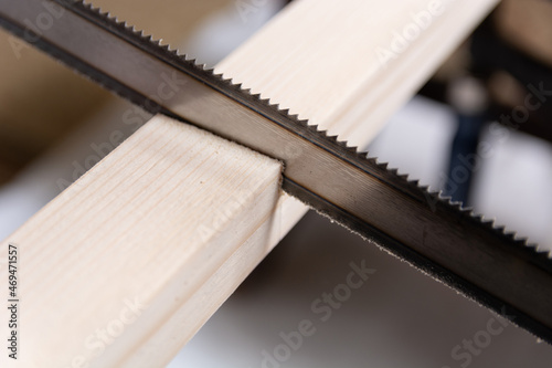 Hand saw cuts a wooden slat in the workshop. Close up, selective focus, and copy space