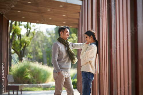 young asian couple talking chatting outdoors in city park