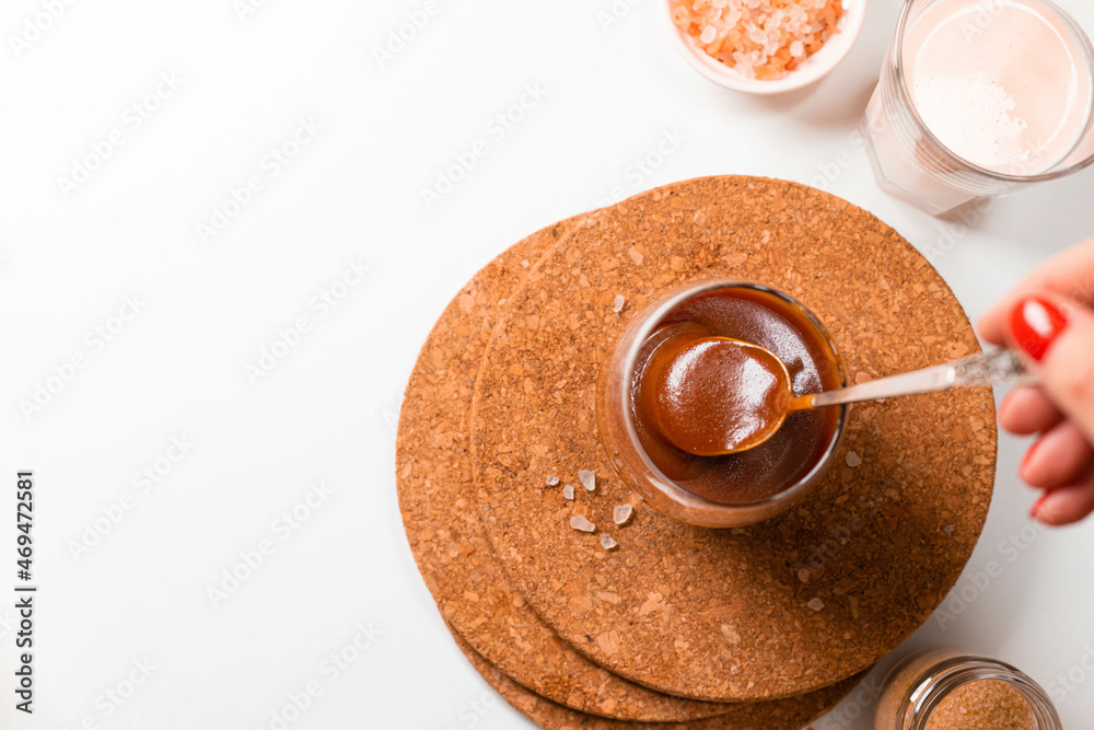 Homemade salted caramel in a glass jar. Delicious sauce with sea salt for ice cream and desserts. Selective focus Homemade salted caramel in a glass jar. Delicious sauce with sea salt for ice cream and desserts. Selective focus