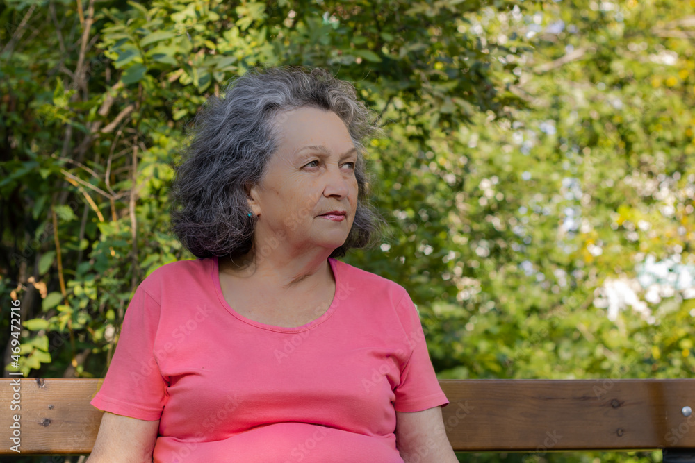An elderly woman with gray hair, freckles and wrinkles on her face. Grandmother in a bright T-shirt looks to the side. An elderly woman with gray hair, freckles and wrinkles on her face. Grandmother in a bright T-shirt looks to the side.