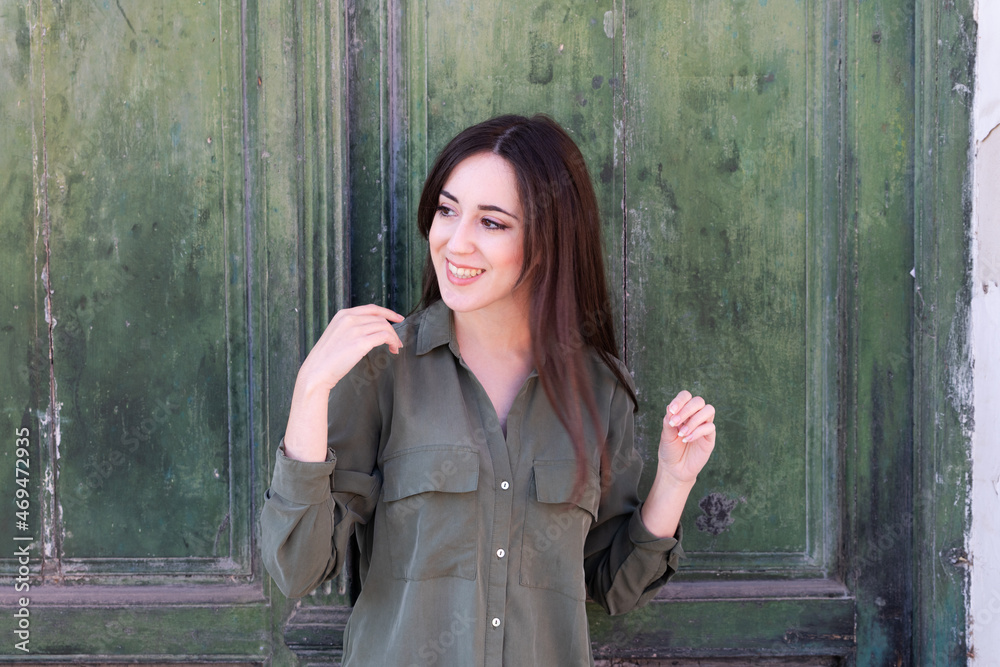 Fototapeta premium Young Brunette stylish lady posing in a green old door background