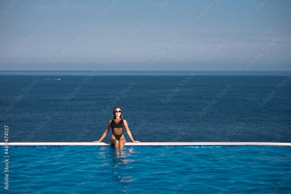 Young woman relaxing in infinity swimming pool looking at view