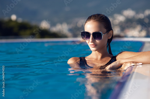 Young woman relaxing in infinity swimming pool looking at view © Admiral