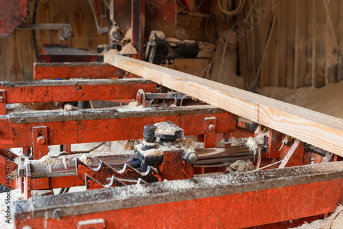 Long timber on woodworking machines. Industrial sawing of boards at a sawmill.