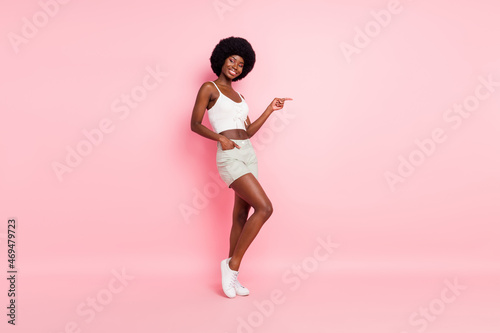 Full length body size photo pretty girl showing finger empty space smiling isolated pastel pink color background