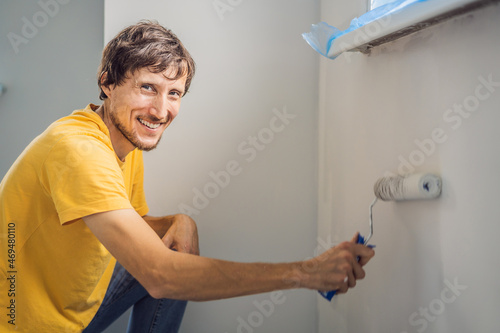 One male house painter worker painting and priming wall with painting roller. DIY