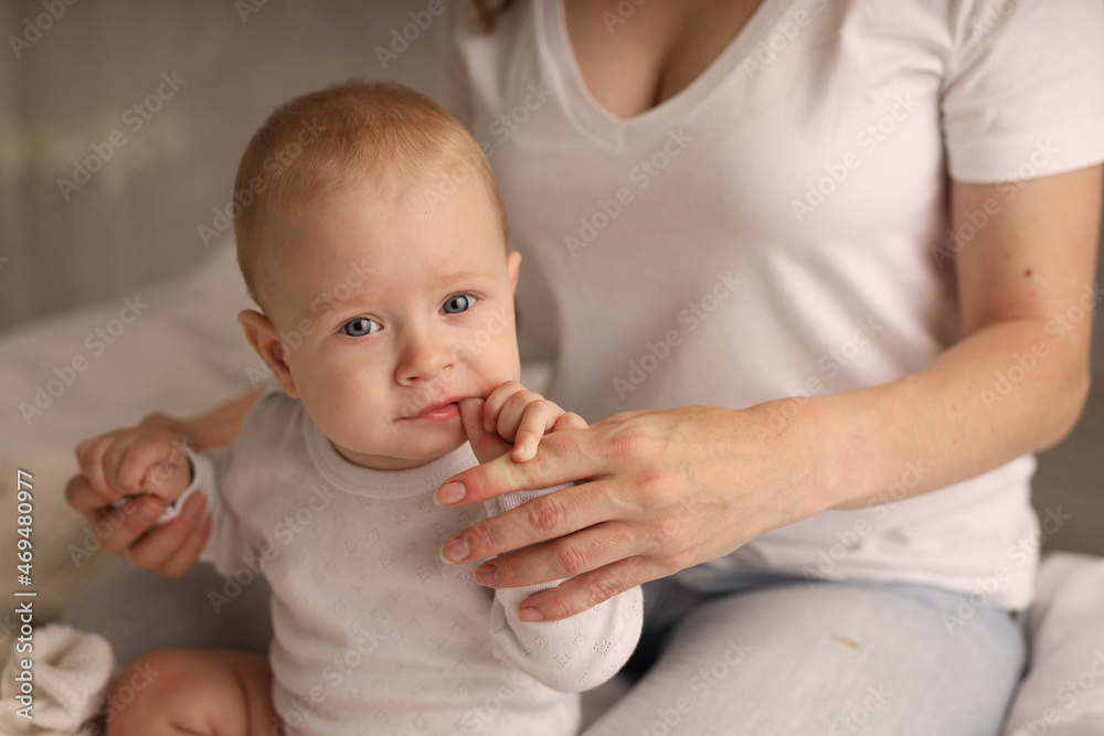 Mom hugs a cute blonde baby on a white bed. motherhood. breastfeeding. High-quality photography Mom hugs a cute blonde baby on a white bed. motherhood. breastfeeding. High-quality photography