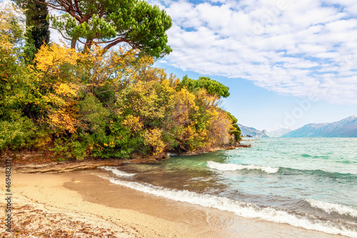 Autumn beach on Lake Garda overlooking the Alps slightly covered with snow