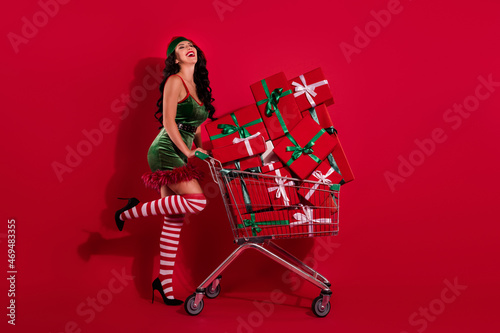 Photo of funny stunning mistress prepare x-mas lusty shopping wear hat elf costume isolated red color background