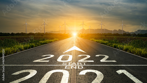 New year 2022 or start straight concept.Word 2022 written on the road in the middle of asphalt road at sunset and destination to wind turbine.Planning,challenge,business strategy,change energy concept