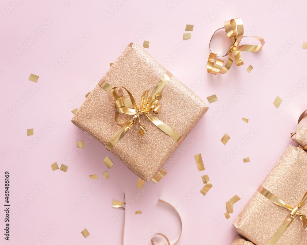 New Year and Christmas gift boxes with golden confetti on pink background, top view, flat lay, winter holidays festive concept New Year and Christmas gift boxes with golden confetti on pink background, top view, flat lay, winter holidays festive concept
