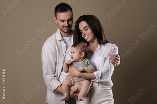 Happy family. Couple with their cute baby on beige background