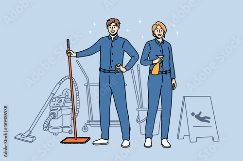 Housework and cleaning workers concept. Young smiling woman and man cleaners in blue uniform standing holding tools for cleaning in hands vector illustration 