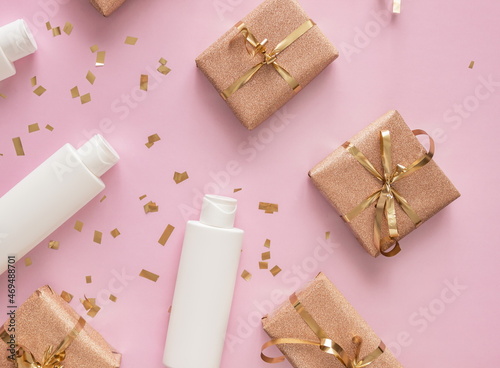 flat lay , cosmetic products, gift boxes , christmas decorations on pink background, top view, copy space.