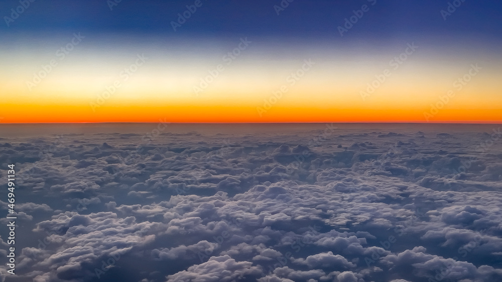 View from the plane to the evening sky, which flies over a thick layer of clouds. The concept of air travel and transportation.