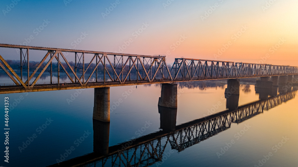 Aerial view of the railway bridge, which is reflected over the calm river Dnieper before dawn in the city center. Sunrise over Kiev, Ukraine.