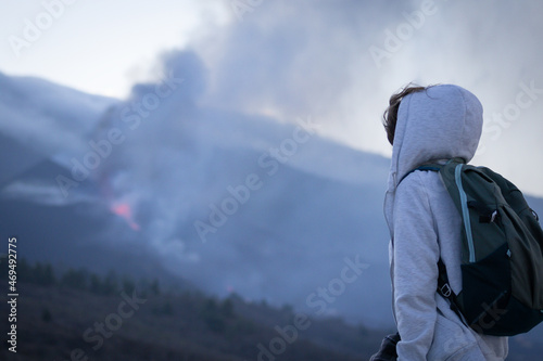 Tourist girl watching Cumbre Vieja volcanic eruption on the island of La Palma, Canary Islands. Volcano La Palma from far. photo