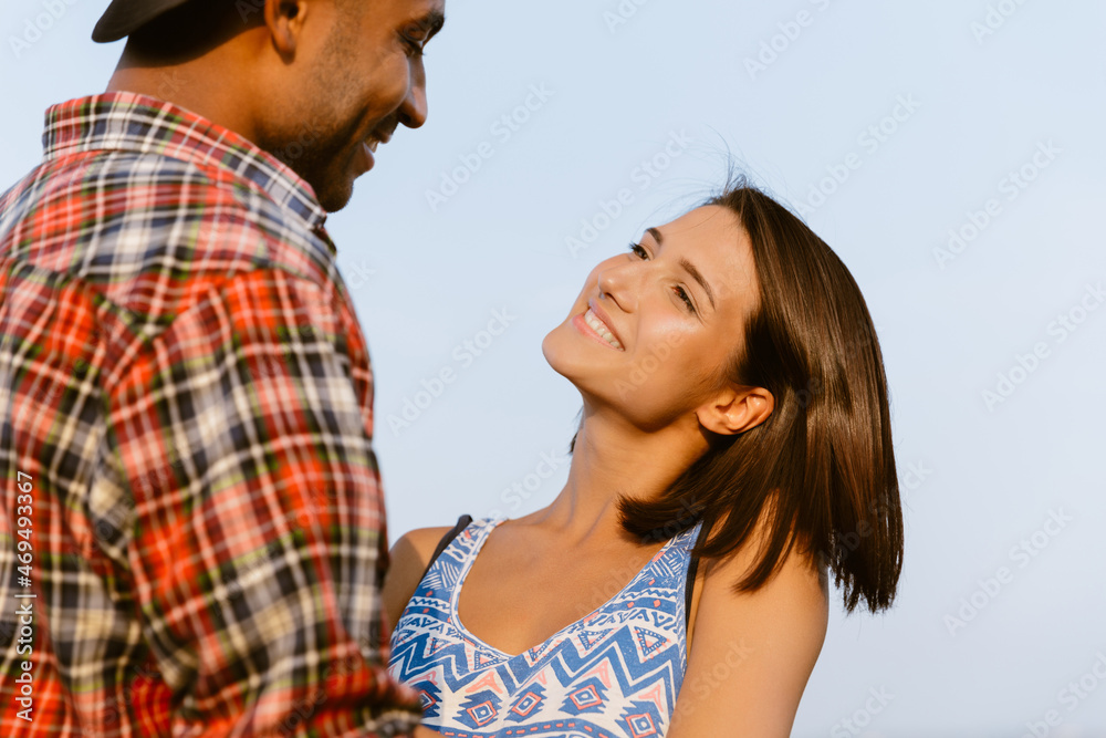 Young multiracial couple smiling and hugging together Young multiracial couple smiling and hugging together