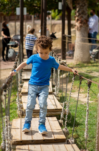 child crossing wooden bridge in playground