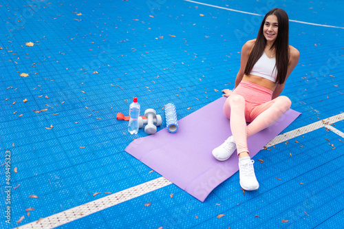 Sporty girl resting on fitness rug.