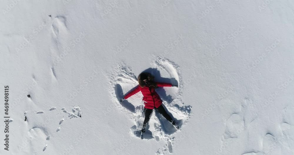 woman lies in the snow and makes an angel