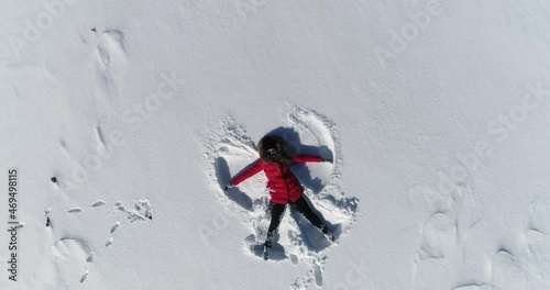 woman lies in the snow and makes an angel