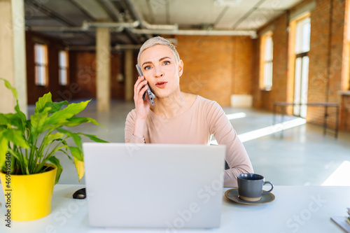 Portrait of nice attractive skilled short-haired middle age woman company owner real estate agency broker agent leader partner talking on cell at modern loft industrial interior workplace workstation.
