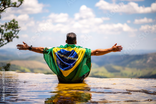 Man with Brazilian flag looking at the horizon. Top of Janela do Ceu Waterfall in Parque Estadual do Ibitipoca (Ibitipoca State Park), Minas Gerais, Brazil photo