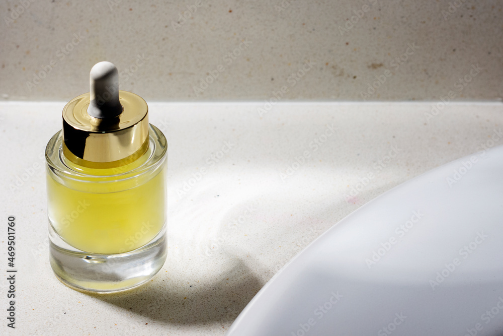 elegant glass bottle with yellow cosmetic serum on top of cabinet top elegant glass bottle with yellow cosmetic serum on top of cabinet top
