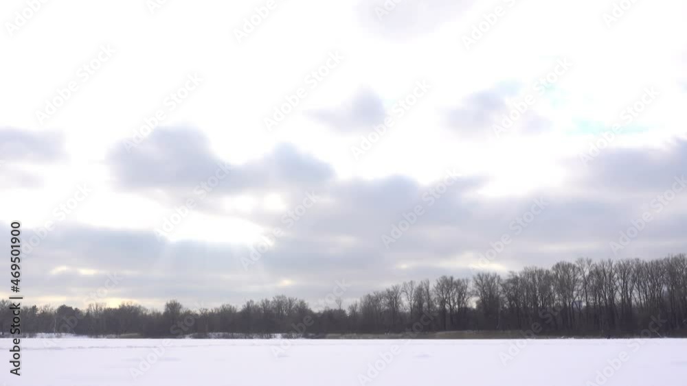 Frozen river and forest covered with snow with floating clouds in time laps. Frozen river and forest covered with snow with floating clouds in time laps.