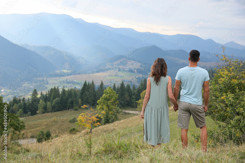 Couple enjoying beautiful mountain landscape, back view. Space for text
