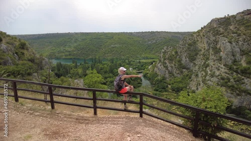 Woman backpacker sitting by the Panoramic aerial view of Krka National Park of Croatia. Sibenik-Knin County and central Dalmatia. photo