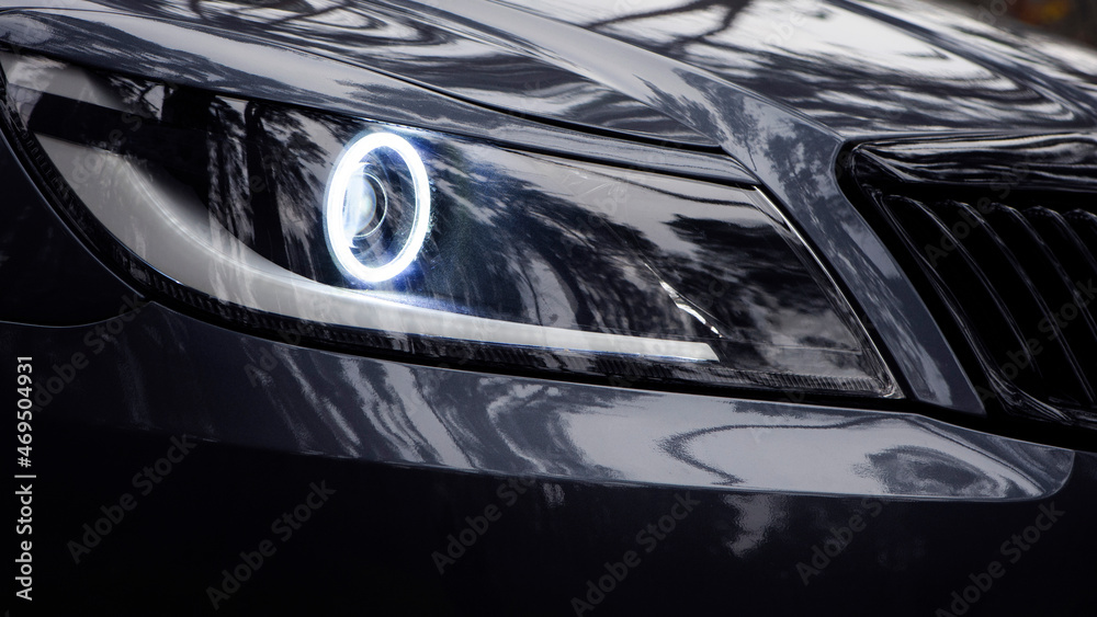 headlight of modern prestigious car closeup. beautiful headlights of a car. dark gray color. part of the front, the car is unrecognizable. glowing headlight, illuminates on a sports car. side view