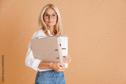 Mature woman in eyeglasses posing with paper folders