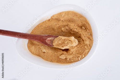 Peruvian maca powder with rustic wooden spoon on a white background. selective focus