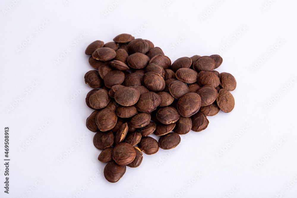 Naklejka premium Sacha Inchi roasted seed nuts, selective focus on front seeds, on white background. heart shape