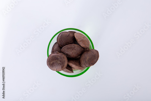 Sacha Inchi roasted seed nuts, selective focus on front seeds, on white background. in a glass