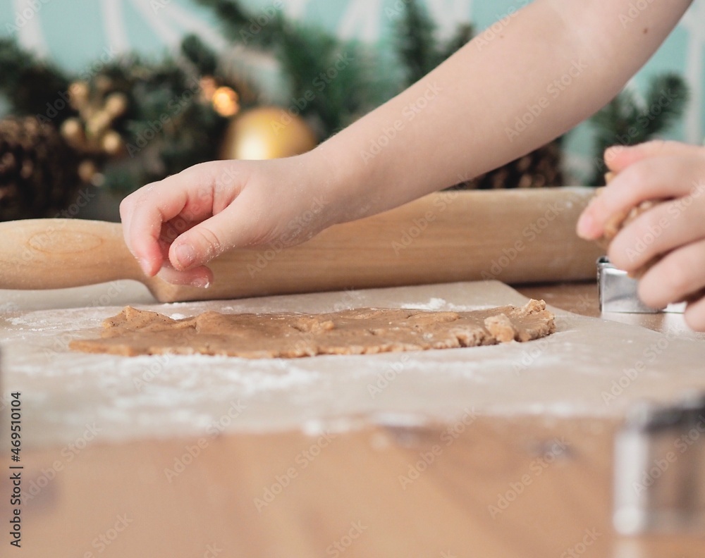 Close-up of children's hands cutting ginger cookies out of dough. Little girl making Christmas cookies. Christmas holidays, moments