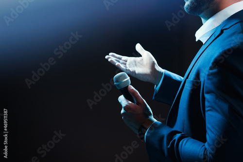 Motivational speaker with microphone performing on stage, closeup. Space for text photo