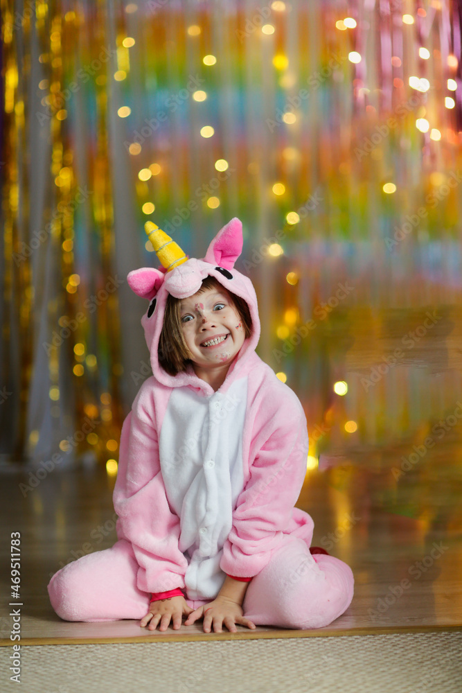 Cute child girl in a soft unicorn costume in pajamas on a colorful