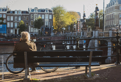 Photography men sitting on the bench near river Amstel
