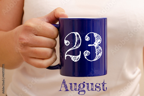 The inscription on the blue cup 23 august. Cup in female hand, business concept