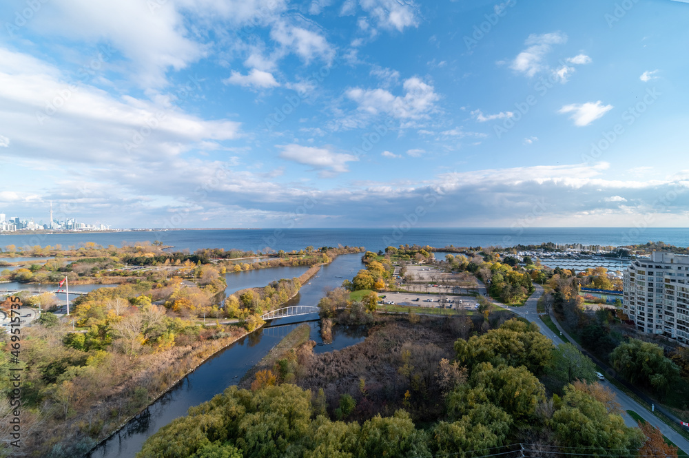 Drone views of Humber bay park  overlooking the lake  and fall tree colours by Parklawn and lakeshore  with blue sky and clouds 