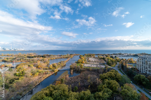 Drone views of Humber bay park overlooking the lake and fall tree colours by Parklawn and lakeshore with blue sky and clouds 
