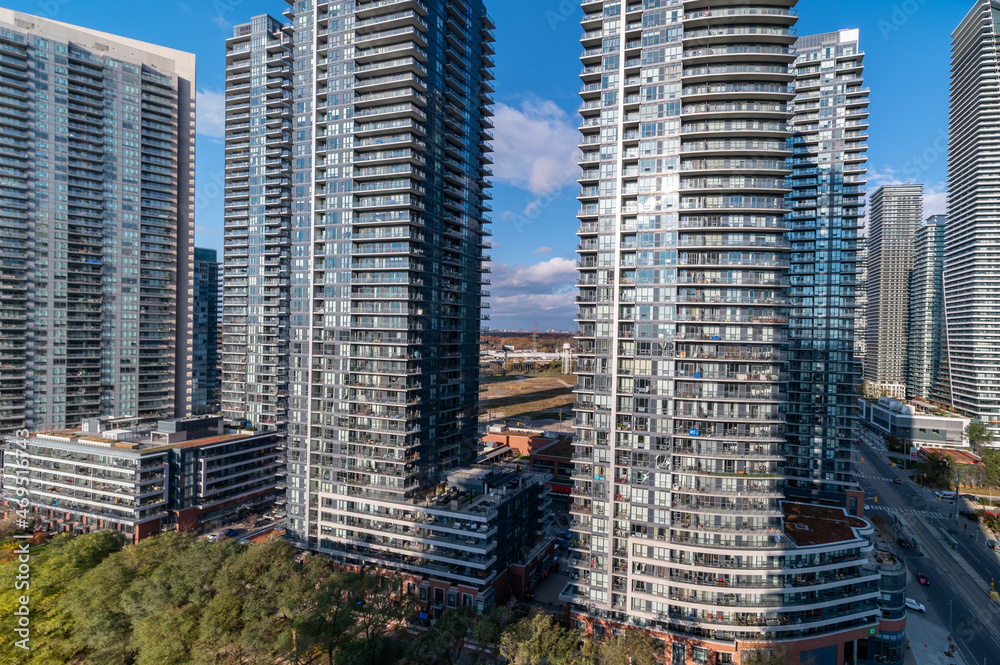 Drone Views of condos and Humber bay shores with  brown trees tops Fall colours by Parklawn rd and lakeshore   with blue skies and broken clouds 