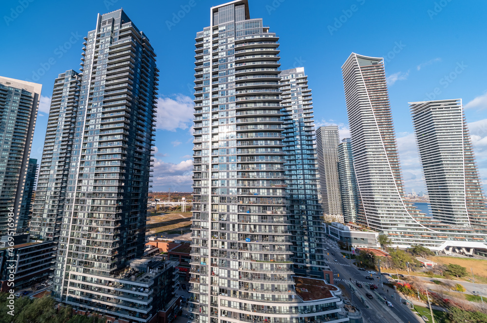 Drone Views of condos and Humber bay shores with  brown trees tops Fall colours by Parklawn rd and lakeshore   with blue skies and broken clouds 